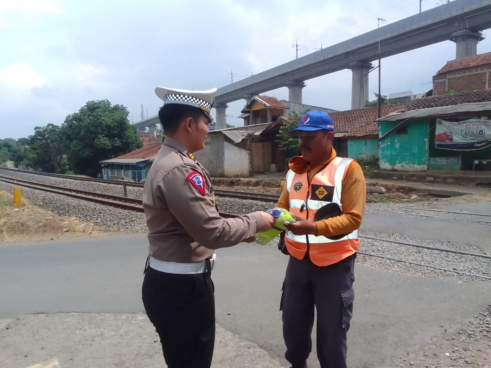 Petugas dari Satuan Lalu lintas Polres Cimahi memberikan batuan rompi, topi dan paket sembako buat para petugas relawan penjaga lintasan kereta api yang berada di Kampung Sumur Bor, Desa Cilame, Kec. Ngamprah. Foto/BANDUNGSATU.COM